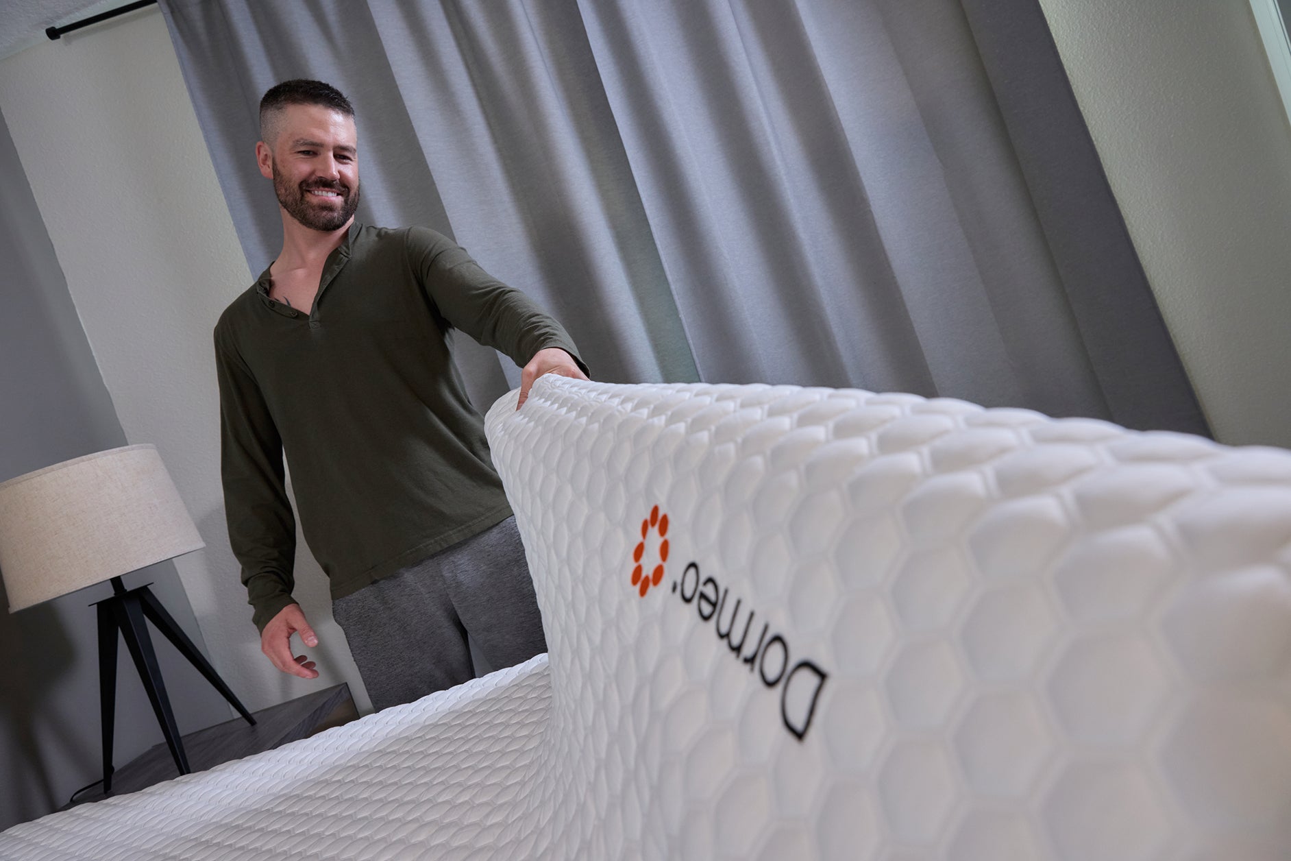 man rolling out a mattress topper